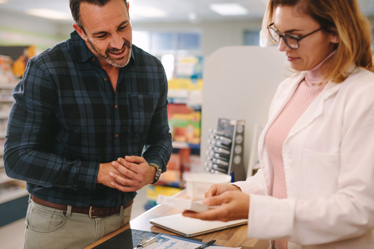 A pharmacist speaks to their patient at the counter Medication therapy management